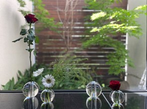 4個並んでいるガラスの一輪挿しに赤いバラと白いガーベラを活けている画像